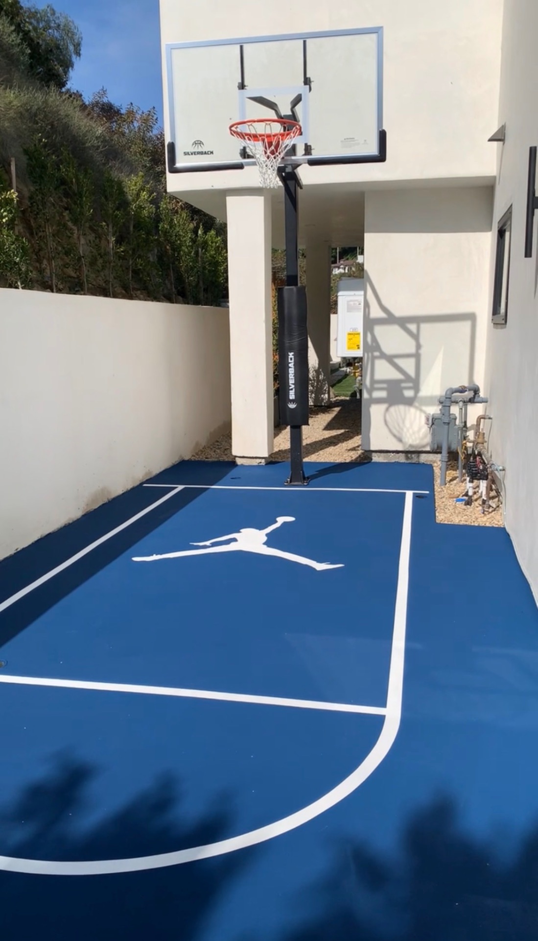 Finished backyard basketball half-court beside a swimming pool in Southern California